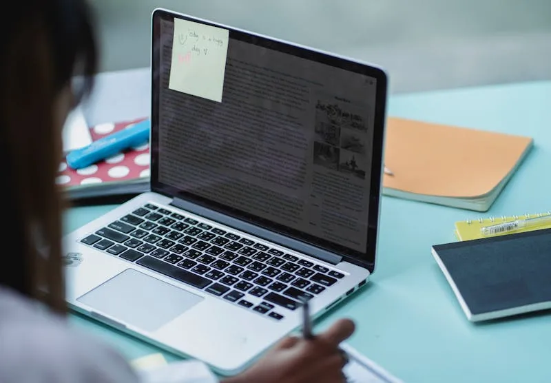 Beginner student taking notes while learning digital skills on a laptop