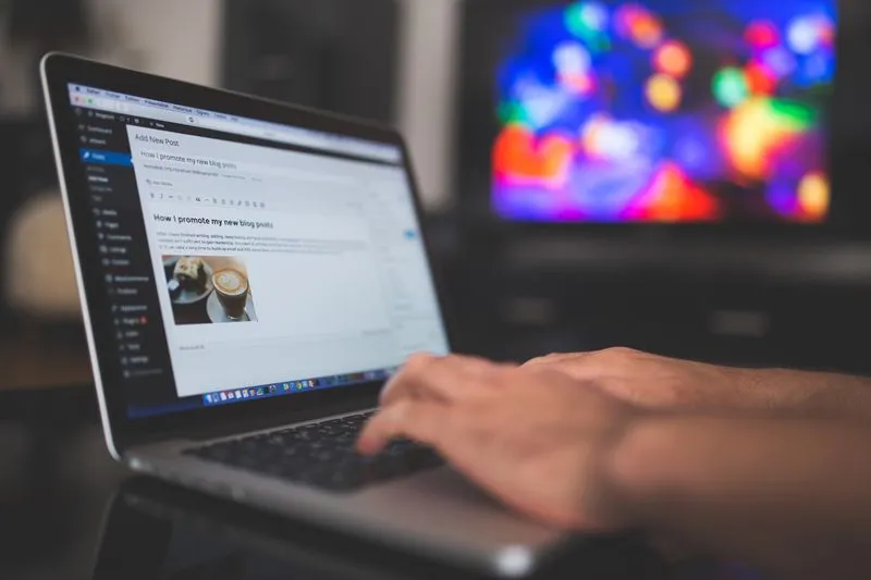 Writer typing a blog post on a laptop at a desk