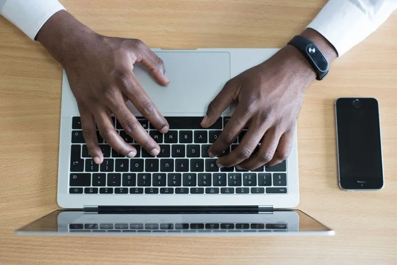 Nigerian business owner using a laptop and smartphone for online marketing