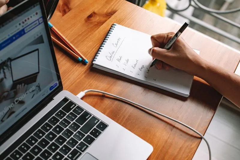 Person learning at a laptop with a notebook
